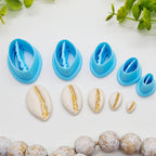 Cowrie shell polymer clay cutters in 5 sizes shown next to finished clay cowrie shell charms