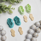 Peanut polymer clay cutters in smooth and textured styles shown next to finished clay peanut charms