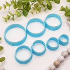 Set of blue circular clay cutters on a white surface with greenery